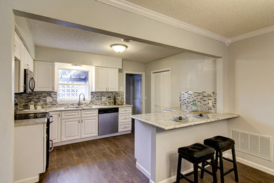 Transitional l-shaped brown floor open concept kitchen photo in Jacksonville with an undermount sink, beaded inset cabinets, white cabinets, multicolored backsplash, glass tile backsplash, stainless steel appliances and a peninsula