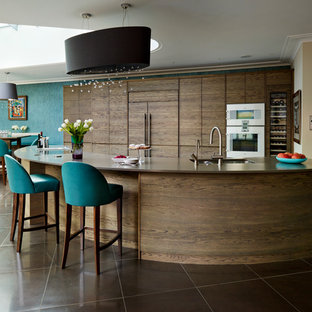 Offene, Geräumige Moderne Küche mit flächenbündigen Schrankfronten, dunklen Holzschränken, Elektrogeräten mit Frontblende, Kücheninsel und Mineralwerkstoff-Arbeitsplatte in London