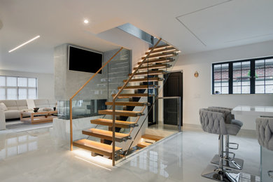 Minimalist wooden open and glass railing staircase photo in New York