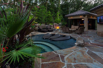 Design ideas for a large tropical backyard patio in Kansas City with a fire feature, natural stone pavers and no cover.
