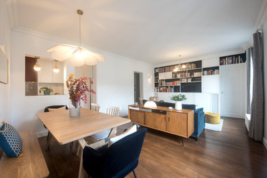 Idées déco pour une salle à manger ouverte sur le salon rétro de taille moyenne avec un mur blanc, parquet foncé, aucune cheminée et un sol marron.