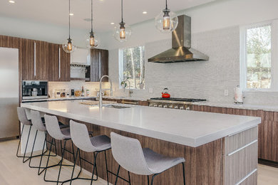 Photo of a large contemporary l-shaped eat-in kitchen in Boston with an undermount sink, flat-panel cabinets, medium wood cabinets, quartz benchtops, white splashback, glass tile splashback, stainless steel appliances, light hardwood floors, with island and white floor.