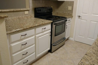 Enclosed kitchen - small transitional galley porcelain tile and beige floor enclosed kitchen idea in San Francisco with a drop-in sink, raised-panel cabinets, white cabinets, granite countertops, beige backsplash, glass tile backsplash, stainless steel appliances, no island and multicolored countertops