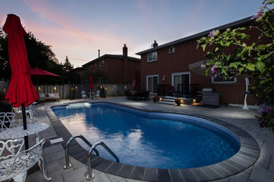 Ejemplo de piscina moderna de tamaño medio tipo riñón en patio trasero con paisajismo de piscina y adoquines de hormigón