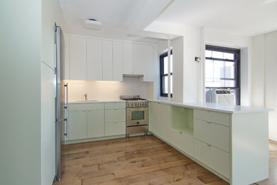 Inspiration for a small contemporary u-shaped medium tone wood floor open concept kitchen remodel in New York with a single-bowl sink, flat-panel cabinets, green cabinets, quartz countertops, white backsplash, ceramic backsplash, stainless steel appliances and no island
