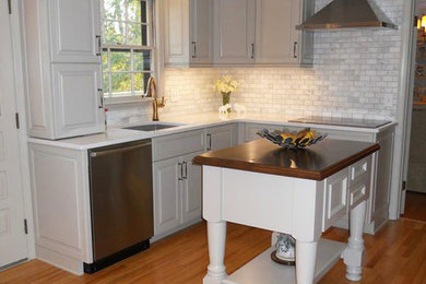 Example of a small classic medium tone wood floor enclosed kitchen design in Atlanta with a single-bowl sink, raised-panel cabinets, gray cabinets, quartz countertops, gray backsplash, stone tile backsplash, stainless steel appliances and an island