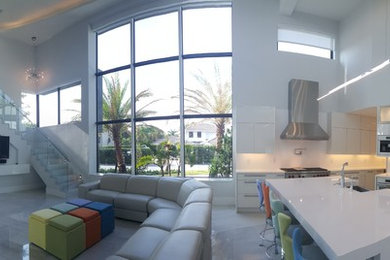 Open concept kitchen - large contemporary single-wall porcelain tile and gray floor open concept kitchen idea in Miami with a farmhouse sink, flat-panel cabinets, white cabinets, solid surface countertops, stainless steel appliances and an island