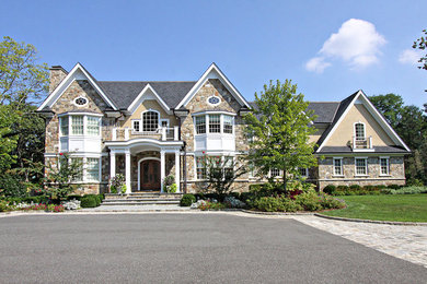 Large elegant yellow two-story mixed siding house exterior photo in New York with a hip roof and a shingle roof