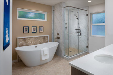 This is an example of a large contemporary master bathroom with shaker cabinets, medium wood cabinets, a freestanding tub, a corner shower, a two-piece toilet, beige tile, mosaic tile, beige walls, vinyl floors, an undermount sink, quartzite benchtops, beige floor, a hinged shower door and white benchtops.