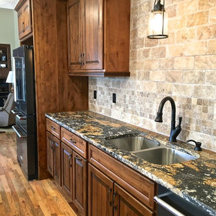 Foto på ett stort kök, med en undermonterad diskho, luckor med upphöjd panel, granitbänkskiva, stänkskydd i travertin, svarta vitvaror, ljust trägolv och en köksö