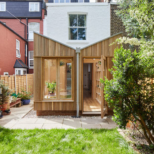 Photo of a modern utility room in London with open cabinets, light wood cabinets, composite countertops, medium hardwood flooring, a concealed washer and dryer, brown floors and yellow worktops.