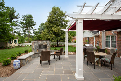 Large transitional backyard stone patio photo in DC Metro with a fireplace and a pergola