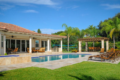 Photo of a mid-sized tropical full sun backyard stone landscaping in Miami.