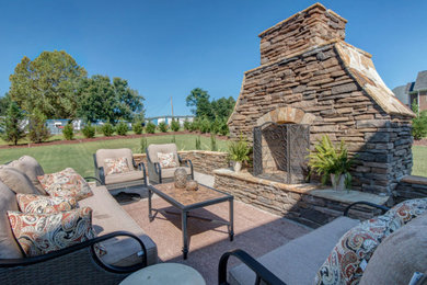 Inspiration for a large timeless backyard concrete paver patio remodel in Raleigh with a fireplace and no cover