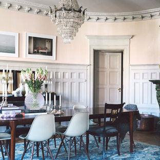 На фото: большая гостиная-столовая в стиле фьюжн с паркетным полом среднего тона, фасадом камина из камня, оранжевыми стенами и печью-буржуйкой с