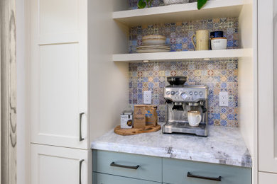 Inspiration for a mid-sized transitional l-shaped eat-in kitchen remodel in Los Angeles with a farmhouse sink, raised-panel cabinets, green cabinets, quartzite countertops, white backsplash, glass tile backsplash, paneled appliances, an island and white countertops