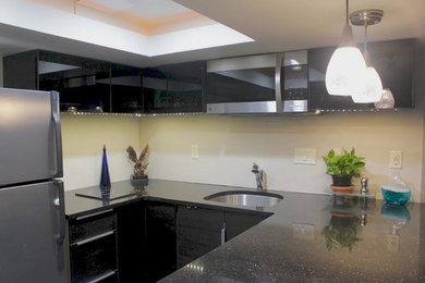 Mid-sized trendy u-shaped eat-in kitchen photo in Minneapolis with a drop-in sink, flat-panel cabinets, black cabinets, laminate countertops, beige backsplash, stainless steel appliances and no island