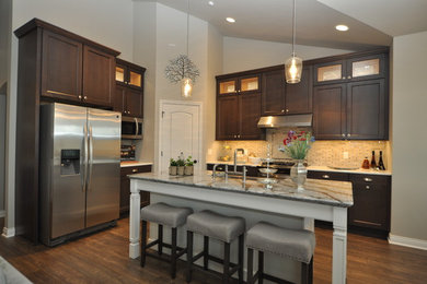 Inspiration for a large shabby-chic style l-shaped dark wood floor open concept kitchen remodel in Milwaukee with a farmhouse sink, shaker cabinets, dark wood cabinets, granite countertops, beige backsplash, porcelain backsplash, stainless steel appliances and an island