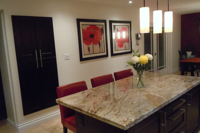 Large trendy l-shaped limestone floor eat-in kitchen photo in Toronto with an undermount sink, raised-panel cabinets, dark wood cabinets, granite countertops, beige backsplash, stone tile backsplash, stainless steel appliances and an island