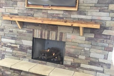 Inspiration for a mid-sized rustic open concept vinyl floor and brown floor living room remodel in Other with a standard fireplace, a stone fireplace and a wall-mounted tv