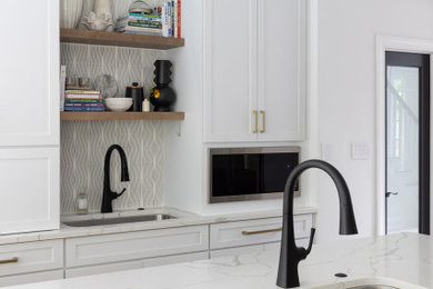 Example of a mid-sized transitional medium tone wood floor, brown floor and exposed beam enclosed kitchen design in DC Metro with an undermount sink, shaker cabinets, white cabinets, quartz countertops, white backsplash, ceramic backsplash, stainless steel appliances, an island and white countertops