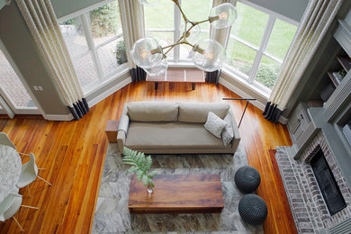 Large trendy loft-style medium tone wood floor living room photo in Atlanta with gray walls, a standard fireplace, a brick fireplace and a media wall