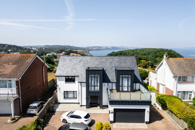 This is an example of a medium sized and white nautical two floor front house exterior in Devon with metal cladding, a pitched roof, a tiled roof and a grey roof.