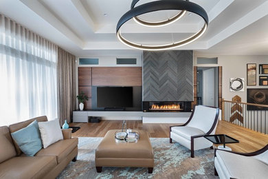 Large trendy formal and open concept medium tone wood floor and gray floor living room photo in Ottawa with gray walls, a standard fireplace, a tile fireplace and a wall-mounted tv