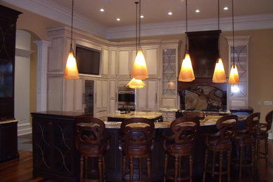 Large elegant l-shaped medium tone wood floor eat-in kitchen photo in Indianapolis with an undermount sink, raised-panel cabinets, white cabinets, granite countertops, yellow backsplash, paneled appliances and two islands