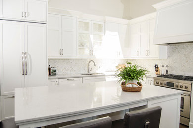 This is an example of a large traditional l-shaped eat-in kitchen in Toronto with an undermount sink, shaker cabinets, white cabinets, quartzite benchtops, white splashback, mosaic tile splashback, panelled appliances, dark hardwood floors and with island.