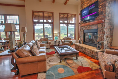 Living room - large rustic open concept medium tone wood floor and brown floor living room idea with beige walls, a standard fireplace, a brick fireplace and a wall-mounted tv