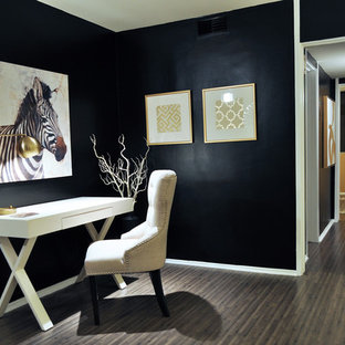 Inredning av ett klassiskt litet hemmabibliotek, med svarta väggar, mörkt trägolv och ett fristående skrivbord