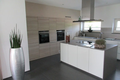 Offene, Große, Zweizeilige Moderne Küche mit Mineralwerkstoff-Arbeitsplatte, Küchenrückwand in Grau, Rückwand aus Keramikfliesen, Küchengeräten aus Edelstahl, Kücheninsel, grauem Boden, flächenbündigen Schrankfronten, weißen Schränken und Porzellan-Bodenfliesen in Stuttgart