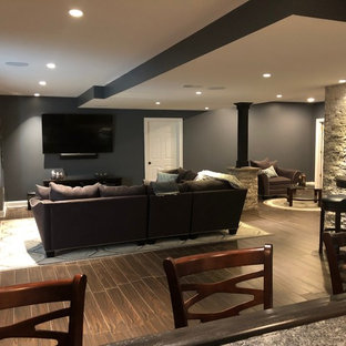 This is an example of a large modern fully buried basement in Philadelphia with grey walls, terracotta flooring and brown floors.