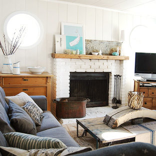 Immagine di un piccolo soggiorno stile marino aperto con pareti grigie, camino classico e cornice del camino in mattoni