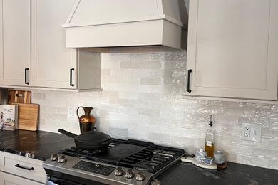Example of a large transitional l-shaped vinyl floor and beige floor eat-in kitchen design in Milwaukee with an undermount sink, shaker cabinets, beige cabinets, granite countertops, white backsplash, subway tile backsplash, stainless steel appliances, two islands and black countertops