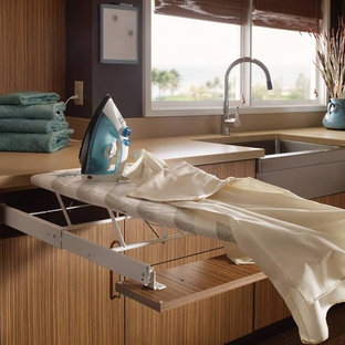 Photo of a medium sized modern separated utility room in Houston with flat-panel cabinets, medium wood cabinets, composite countertops, brown walls, carpet and a belfast sink.