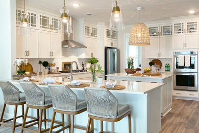 Example of a large beach style kitchen design in Charleston with white cabinets, white backsplash, subway tile backsplash, stainless steel appliances, an island and white countertops