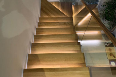 This is an example of a medium sized contemporary wood floating glass railing staircase in Hampshire.