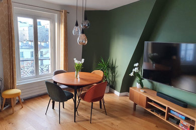 Aménagement d'une salle de séjour moderne de taille moyenne et ouverte avec un mur vert, un sol en bois brun, aucune cheminée, un téléviseur fixé au mur, un sol marron et éclairage.