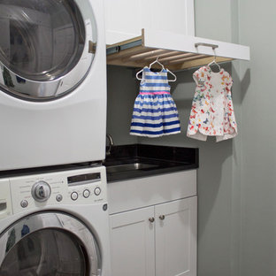 シカゴの中サイズのトランジショナルスタイルのおしゃれな家事室 (アンダーカウンターシンク、シェーカースタイル扉のキャビネット、白いキャビネット、御影石カウンター、グレーの壁、セラミックタイルの床、上下配置の洗濯機・乾燥機、グレーの床) の写真