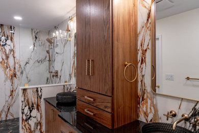 Mid-sized trendy master multicolored tile and porcelain tile porcelain tile, multicolored floor and double-sink bathroom photo in Philadelphia with flat-panel cabinets, medium tone wood cabinets, a one-piece toilet, white walls, a vessel sink, quartz countertops, black countertops, a built-in vanity and a niche