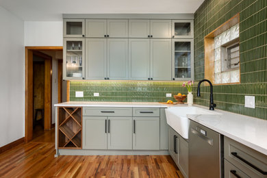 Eat-in kitchen - large modern l-shaped medium tone wood floor and brown floor eat-in kitchen idea in Chicago with a farmhouse sink, shaker cabinets, green cabinets, quartz countertops, green backsplash, porcelain backsplash, stainless steel appliances and white countertops