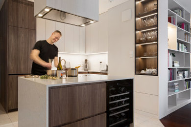 Große Moderne Küche mit Einbauwaschbecken, flächenbündigen Schrankfronten, dunklen Holzschränken, Quarzit-Arbeitsplatte, Küchenrückwand in Weiß, Rückwand aus Quarzwerkstein, schwarzen Elektrogeräten, dunklem Holzboden, Kücheninsel und weißer Arbeitsplatte in Berlin