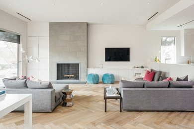 Inspiration for a contemporary open concept living room in Houston with white walls, light hardwood floors, a standard fireplace, a tile fireplace surround and a wall-mounted tv.