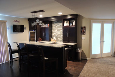 Mid-sized elegant single-wall dark wood floor seated home bar photo in Detroit with shaker cabinets, dark wood cabinets, granite countertops, glass tile backsplash and beige backsplash