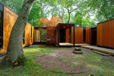 Inspiration for a midcentury one-storey brown house exterior in Milwaukee with wood siding and a flat roof.