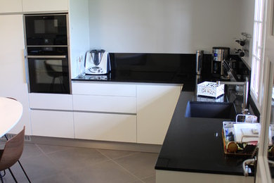 Photo of a mid-sized contemporary l-shaped separate kitchen in Angers with quartz benchtops, black splashback, stainless steel appliances, with island and grey floor.