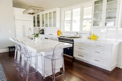 Large trendy l-shaped dark wood floor and brown floor eat-in kitchen photo in Hawaii with an undermount sink, shaker cabinets, white cabinets, marble countertops, white backsplash, subway tile backsplash, paneled appliances and an island