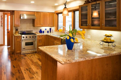 Inspiration for a mid-sized craftsman u-shaped dark wood floor eat-in kitchen remodel in Santa Barbara with a double-bowl sink, recessed-panel cabinets, medium tone wood cabinets, granite countertops, beige backsplash, stone tile backsplash, stainless steel appliances and a peninsula